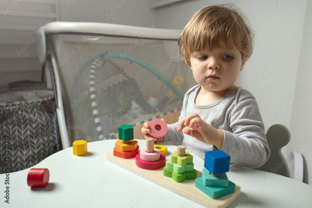 Beautiful toddler play with a wooden toys at home. Toddler play with a color educational toy. Child play at the table in the baby room. Child development. Funny baby. Lifestyle. Beautiful toddler play with a wooden toys at home. Toddler play with a color educational toy. Child play at the table in the baby room. Child development. Funny baby. Lifestyle.