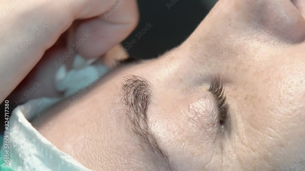In the eyebrow beauty salon, the master takes care of the eyebrows. Design and coloring styling and lamination of female eyebrows. Color matching. Correction with a cosmetic tool.