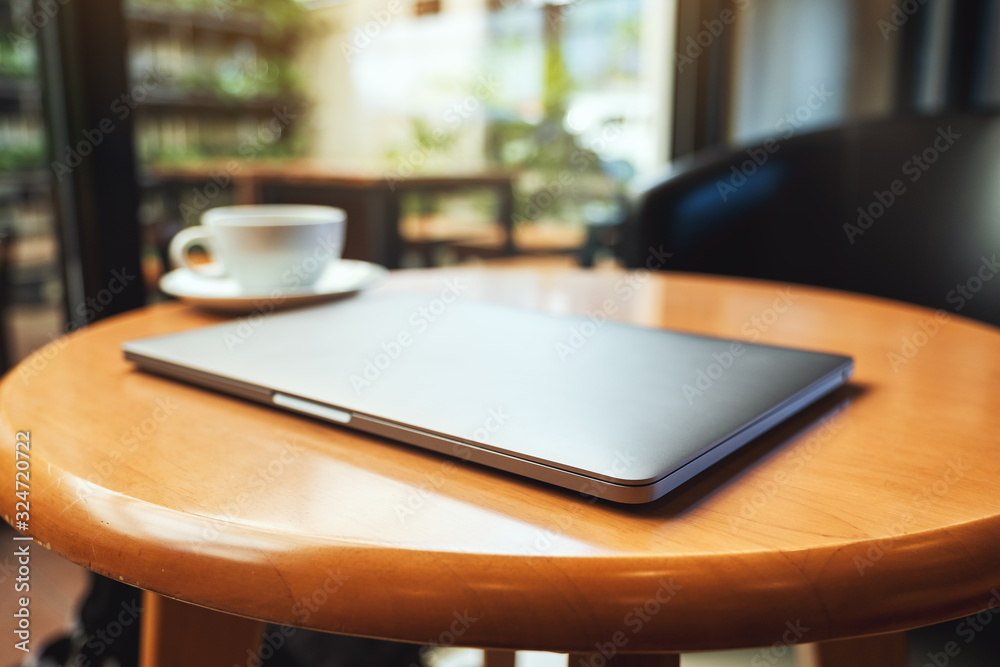 A single laptop computer with a coffee cup on wooden table A single laptop computer with a coffee cup on wooden table