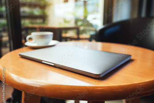 A single laptop computer with a coffee cup on wooden table