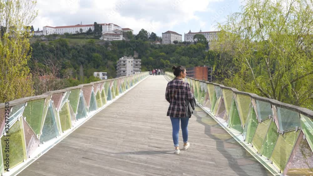 Woman traveler walking on a city bridge in Coimbra, Portugal
