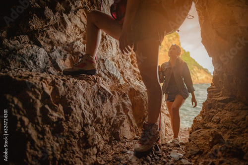 Side view of woman hiker climbing on the cliff at cave in sunset. Woman, hiking, hikers, mountain, cave, activity concept.