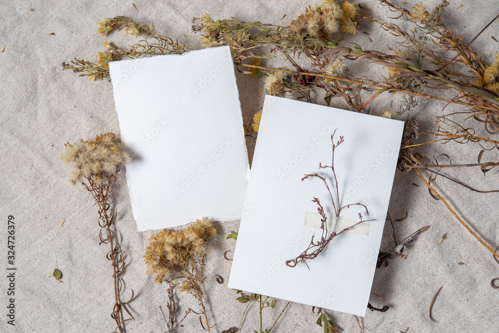 Wedding invitation mockup with dry plants , old papers on grey textile background. Top view, flat lay. Wedding stationary. Perfect for presentation of your invitation, menu, greeting cards