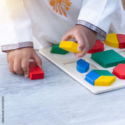 Close up hand of little Muslim boy with tradition suit playing colorful wood blocks in the park, education concept