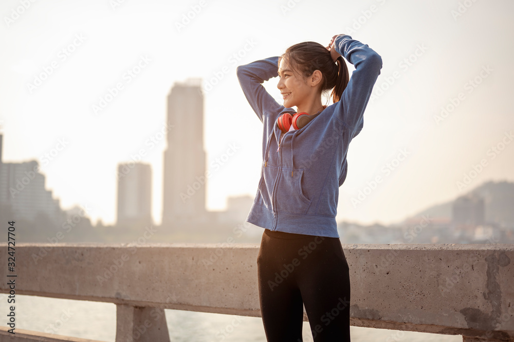 Women tied their hair in preparation for a morning exercise in the city. City running Healthy living in the capital. City view behind.  Exercise, fitness, jogging, running, lifestyle, healthy concept. - obrazy, fototapety, plakaty 