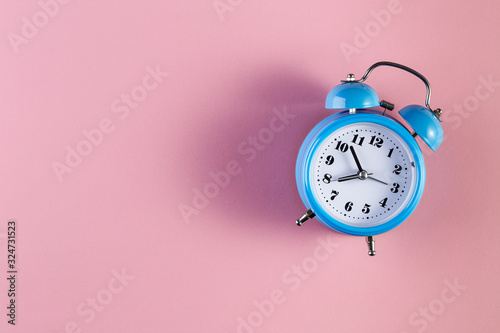 Blue vintage alarm clock on light pink color background. Alarm clock with place for text. Time management concept, business planning