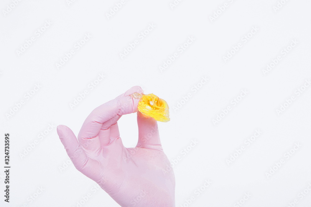 wax for depilation close-up. The girl demonstrates a cosmetic product. The doctor's gloved hand. Sugaring: hair removal with liquid sugar. This is a less painful hair removal with wax replacement