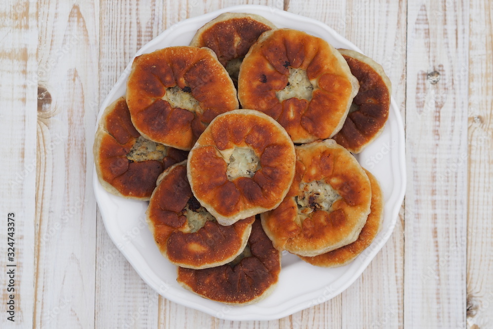 Belyasha homemade baking with meat on a white rustic wooden table. Belyasha homemade baking with meat on a white rustic wooden table.