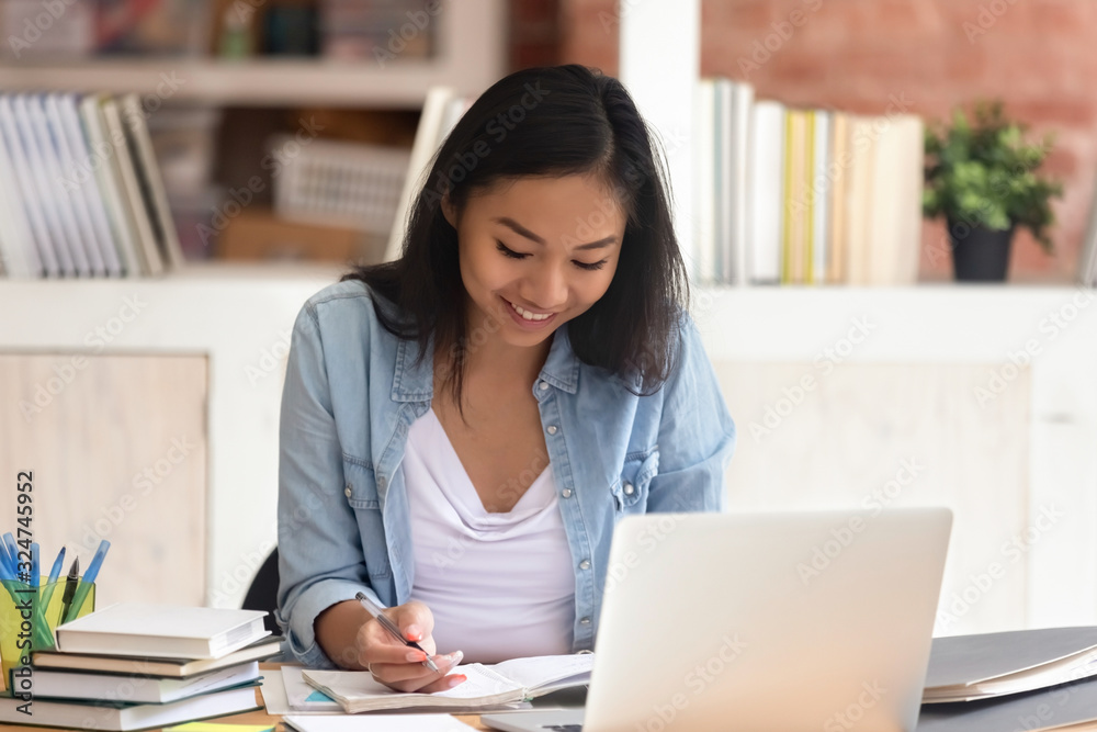 Attractive smiling Asian woman student studying with books and laptop Attractive smiling Asian woman student studying with books and laptop