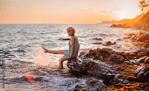 One young beautiful girl splashes and splashes the sea at sunset. Summer landscape sea, Islands and orange sunlight. © shangarey