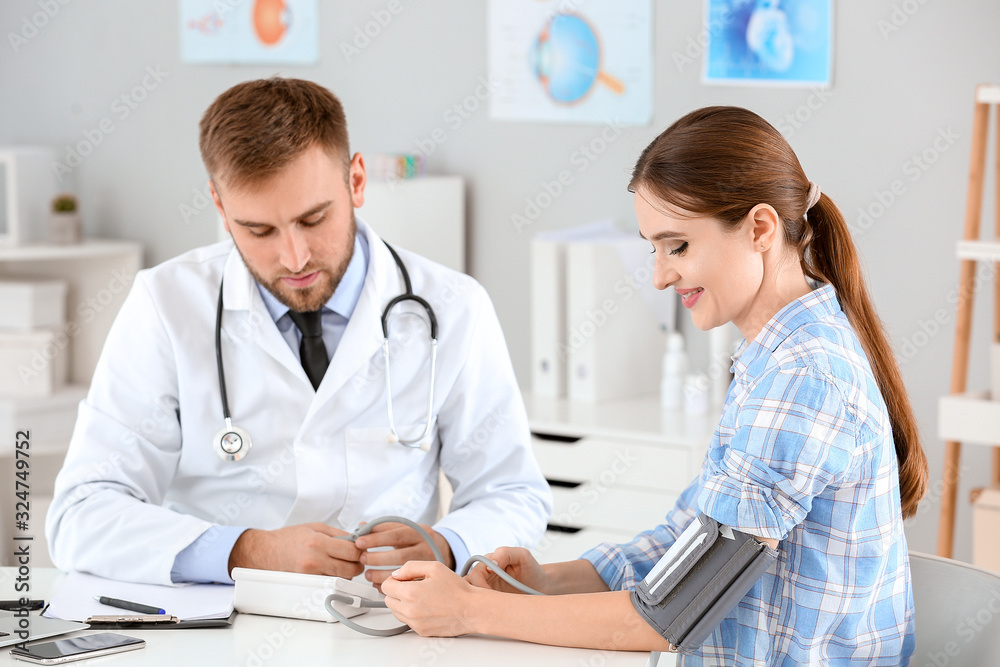 Male doctor measuring blood pressure of female patient in hospital Male doctor measuring blood pressure of female patient in hospital