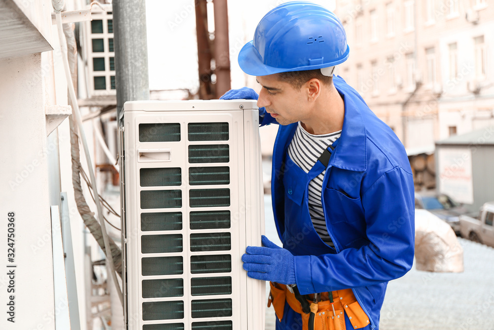 Male technician installing outdoor unit of air conditioner Male technician installing outdoor unit of air conditioner