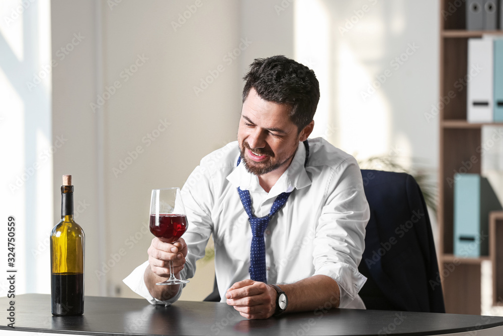 Businessman drinking wine in office. Concept of alcoholism Businessman drinking wine in office. Concept of alcoholism