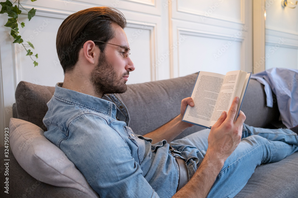 Single male sitting in living room and relaxing with book