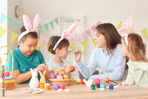 Little children with mother painting Easter eggs at home