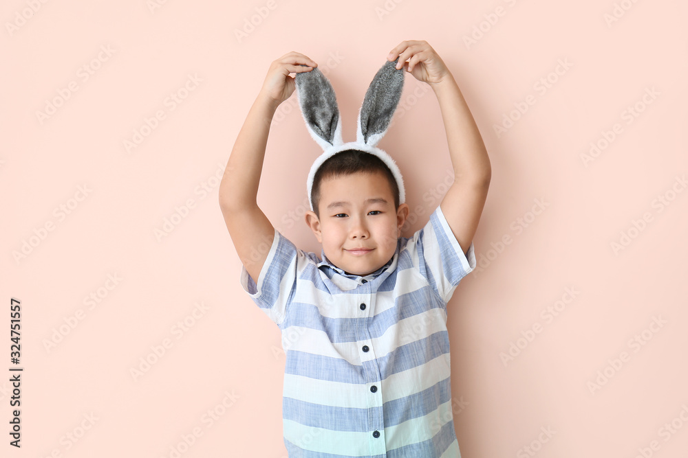 Little Asian boy with bunny ears on color background Little Asian boy with bunny ears on color background