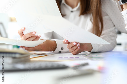 Focus on tender female hands holding important business documents with significant charts and graphs used for special corporation analysis. Accounting office concept. Blurred background photo