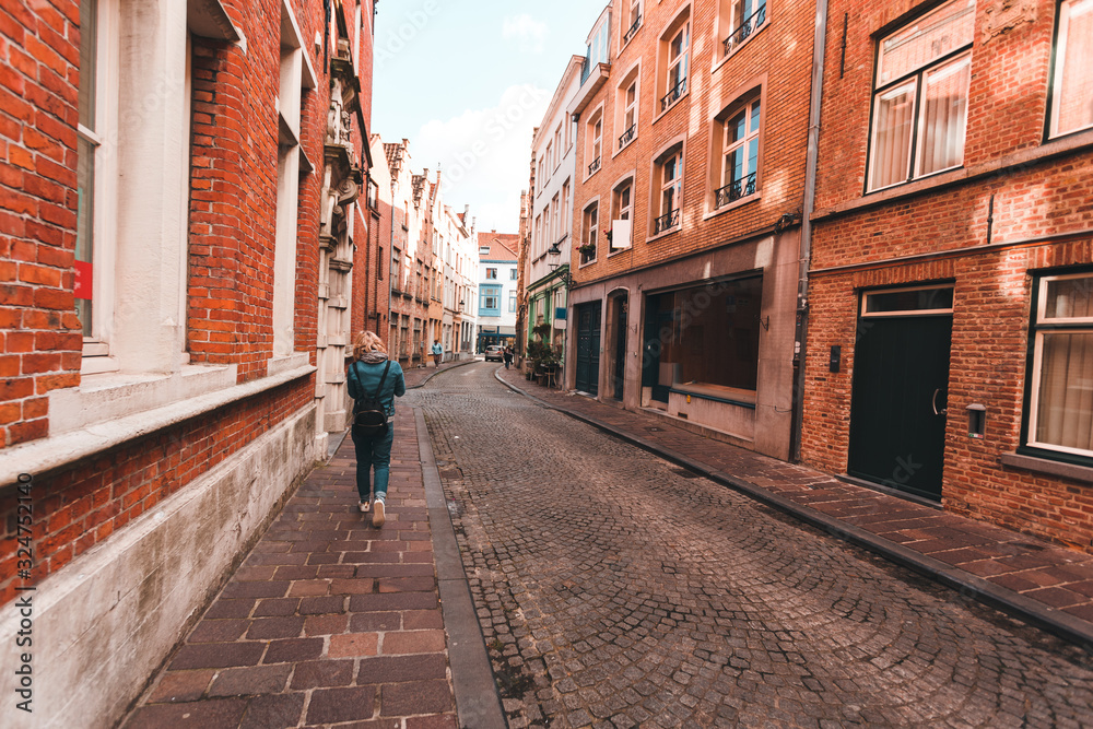 A woman walks along an empty street in Bruges, Belgium.