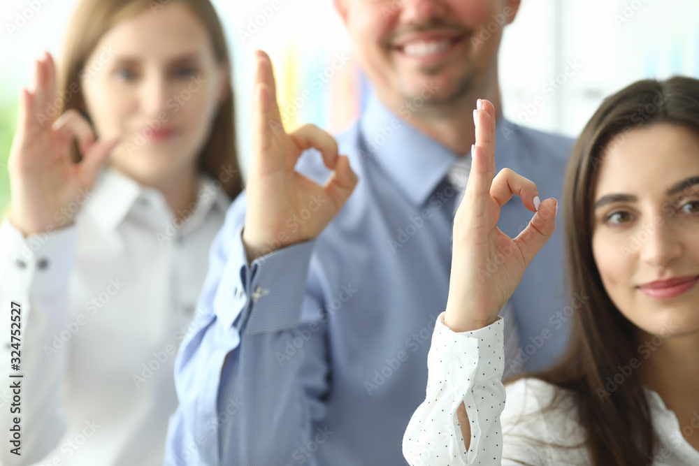 Focus on businesspeople demonstrating ok symbol. Smiling colleagues posing at modern office and looking at camera with gladness. Friendly teamwork concept Focus on businesspeople demonstrating ok symbol. Smiling colleagues posing at modern office and looking at camera with gladness. Friendly teamwork concept