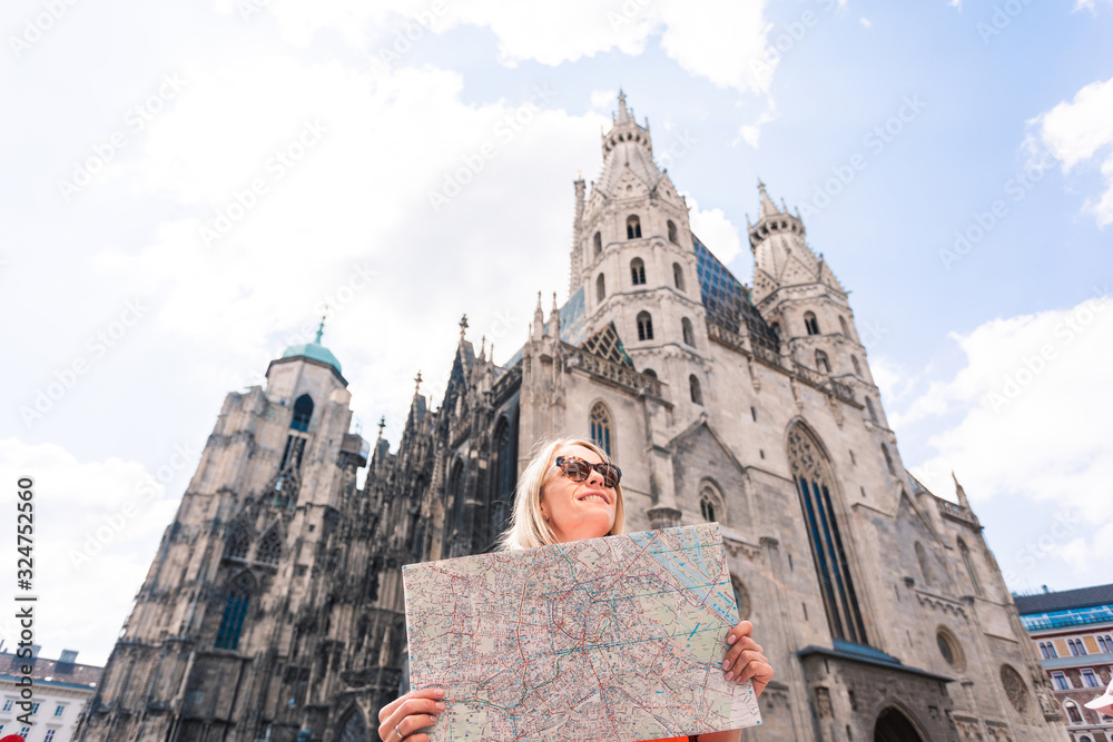 Fototapeta premium A young woman in a bright orange dress stands on the background of St. Stephen's Cathedral in Vienna, Austria
