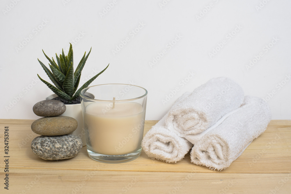 Spa, relaxation and relaxation. Candle, towel, stones and a flower on a wooden and white background.