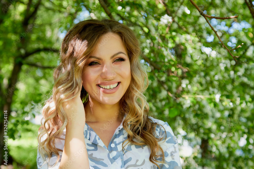Portrait of a beautiful blonde girl with green eyes and blossoming apple tree with white flower in the park in a spring time Portrait of a beautiful blonde girl with green eyes and blossoming apple tree with white flower in the park in a spring time