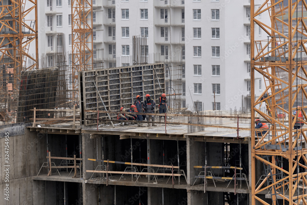 A lot of builders in helmets and masks on the top floor of a house under construction