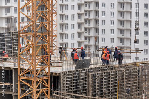 A lot of builders in helmets and masks on the top floor of a house under construction photo