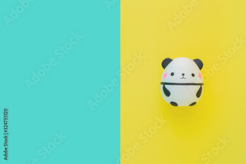 Flat lay antistress toy squish black white cute panda with pink cheeks.Bright yellow blue background.Compressing, soft, squeezable items to relieve stress, problems, anxieties, worries.Summer concept