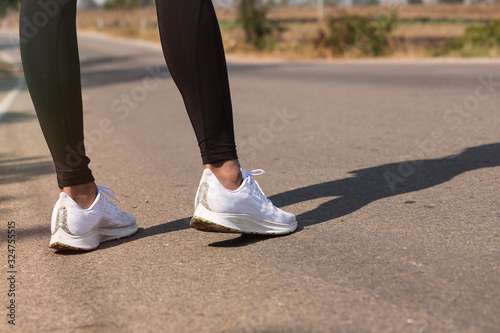 Close up Athlete running woman wearing Exercise pants and running shoe on the road,Runner woman traning in the morning.Walking for warm up her muscle.