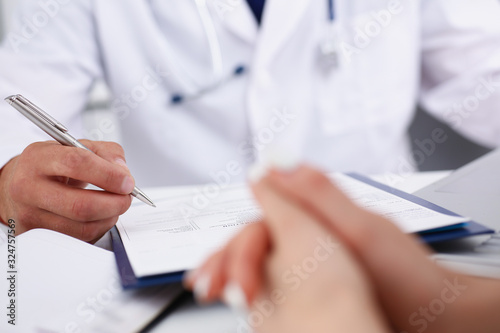 Male doctor arm hold silver pen filling patient complaints list clipped to pad. Physical problem exam er disease prevention ward round visitor check prescribe remedy healthy lifestyle concept