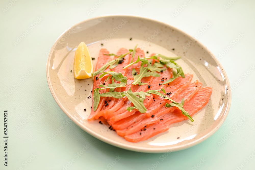 Close-up of smoked salted salmon served with herbs and lemon on a white plate with blue mint background. Close-up of smoked salted salmon served with herbs and lemon on a white plate with blue mint background.