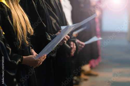 Choir singers holding musical score and singing on student gradu photo