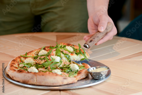 Fototapeta Naklejka Na Ścianę i Meble -  Delicious Italian large pizza served on a light wooden table in a restaurant. Restaurant food photography