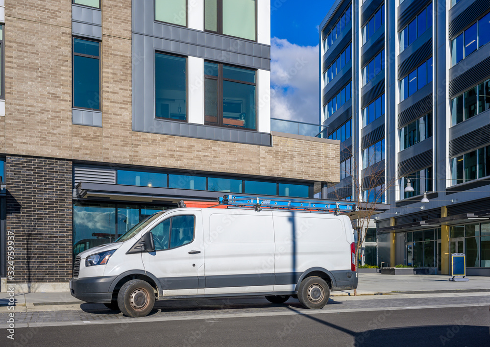 Commercial compact mini van for small business and deliveries standing on urban city street with multilevel apartments buildings Commercial compact mini van for small business and deliveries standing on urban city street with multilevel apartments buildings