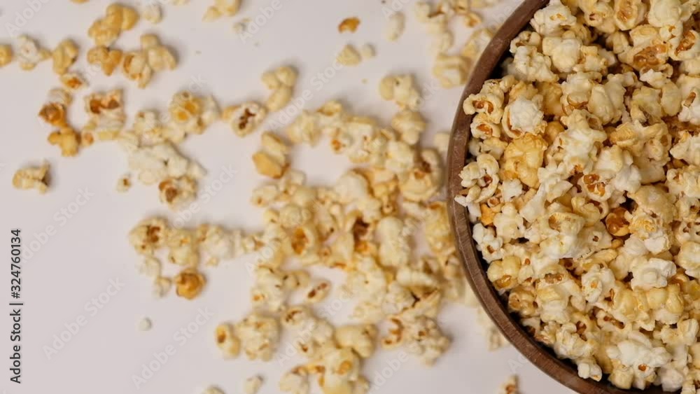 Popcorn tossed in a wooden bowl on a white background. Slow Motion video. Close up top view Popcorn tossed in a wooden bowl on a white background. Slow Motion video. Close up top view