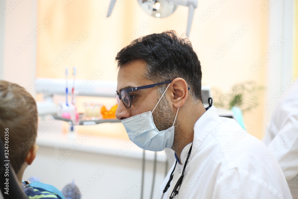 dentist is diagnosing the child while assistant in dental clinic dentist is diagnosing the child while assistant in dental clinic