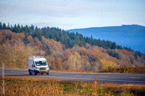 Compact commercial mini van running on the spectacular autumn road