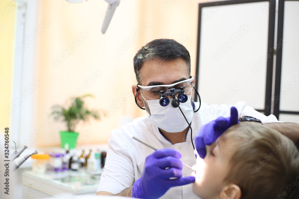 dentist is diagnosing the child while assistant in dental clinic dentist is diagnosing the child while assistant in dental clinic