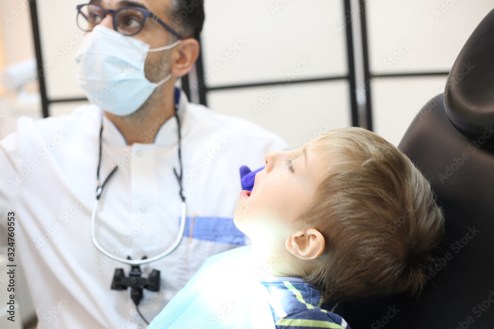 dentist is diagnosing the child while assistant in dental clinic dentist is diagnosing the child while assistant in dental clinic