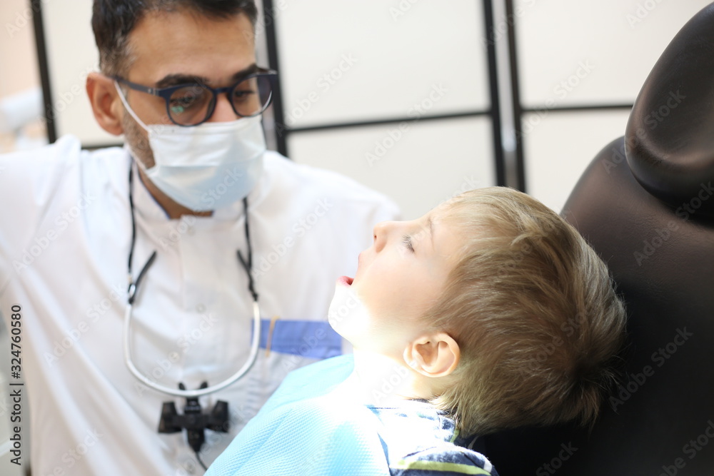 dentist is diagnosing the child while assistant in dental clinic dentist is diagnosing the child while assistant in dental clinic