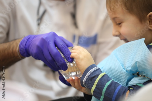 dentist is diagnosing the child while assistant in dental clinic