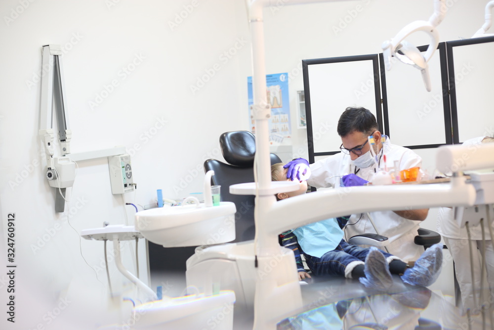 dentist is diagnosing the child while assistant in dental clinic dentist is diagnosing the child while assistant in dental clinic