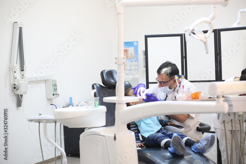 dentist is diagnosing the child while assistant in dental clinic