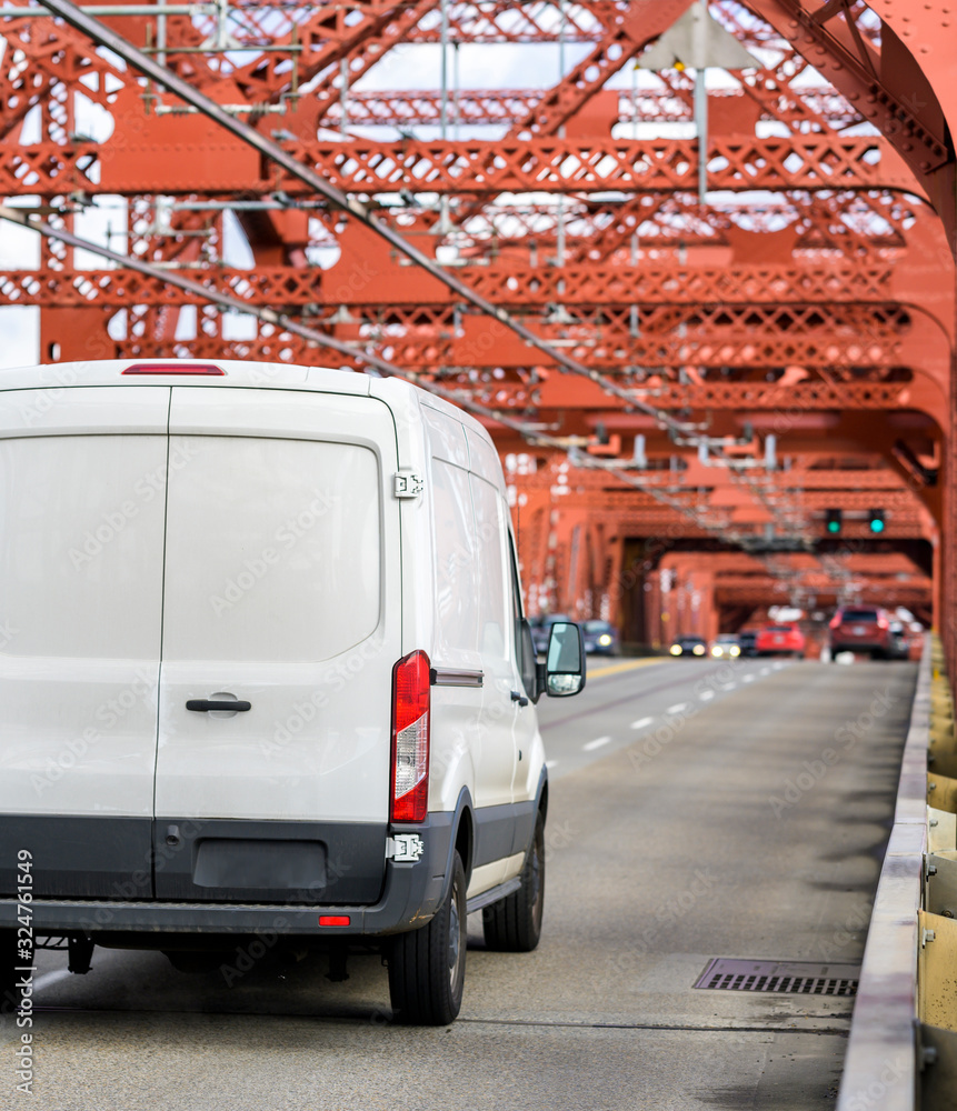 White commercial cargo mini van driving on the red truss bridge
