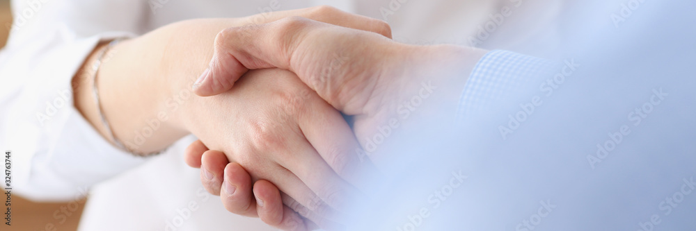 Businessman and woman shake hands as hello in office closeup. Friend welcome introduction greet or thanks gesture product advertisement partnership approval arm strike a bargain on deal concept Businessman and woman shake hands as hello in office closeup. Friend welcome introduction greet or thanks gesture product advertisement partnership approval arm strike a bargain on deal concept