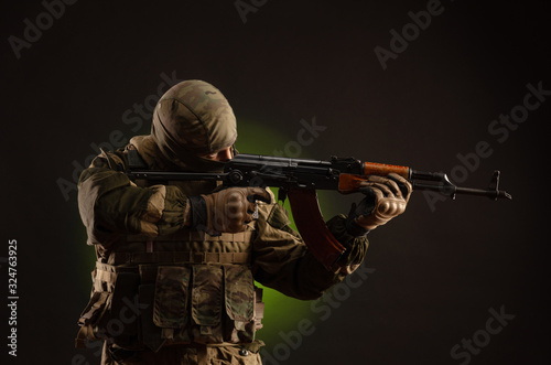 soldier militia saboteur in military clothing with a Kalashnikov rifle on a dark background