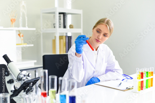 Young female scientist doing some research working conduct experiments and microscope in modern laboratory - Scientists in lab biochemistry genetics forensics microbiology and test tube female doctor