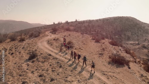 Group of hikers crossing hill top in sunny and hot day. Aerial drone shot from above Jordan, Dana Biosphere Reserve photo