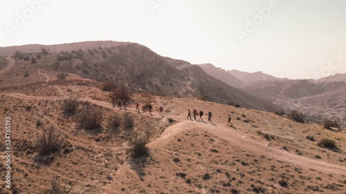 Group of hikers crossing hill top in sunny and hot day. Aerial drone shot from above photo